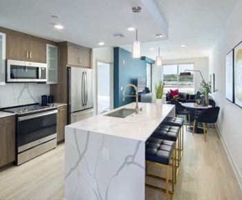 a kitchen with a large island and a dining room with a table and chairs